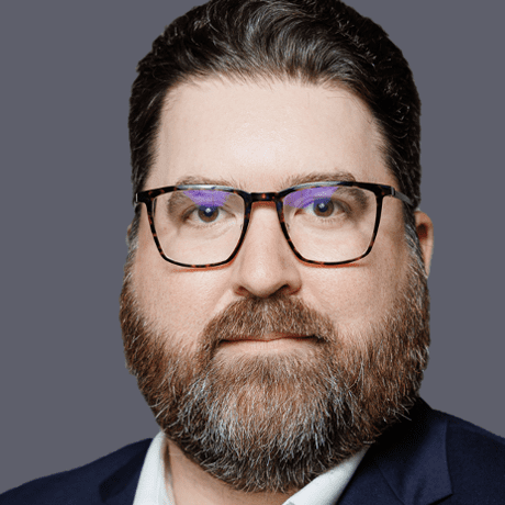 A man with beard and glasses in a suit.
